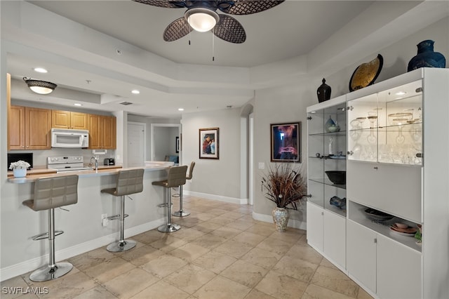 kitchen featuring a breakfast bar, ceiling fan, and white appliances