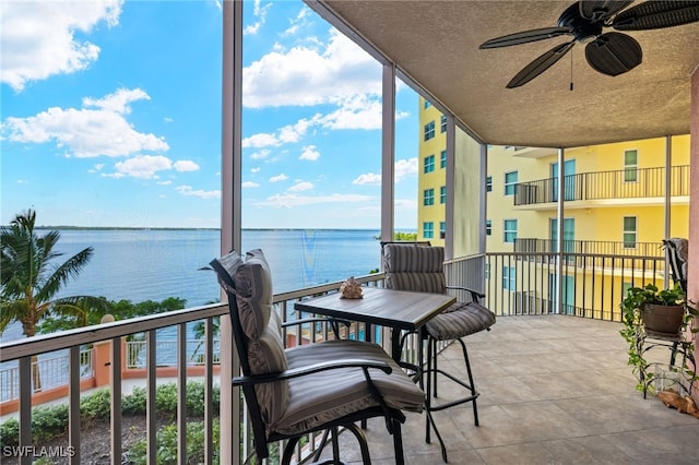 sunroom / solarium with a water view and ceiling fan