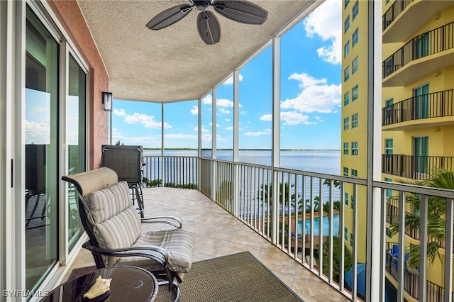 sunroom with a water view and ceiling fan