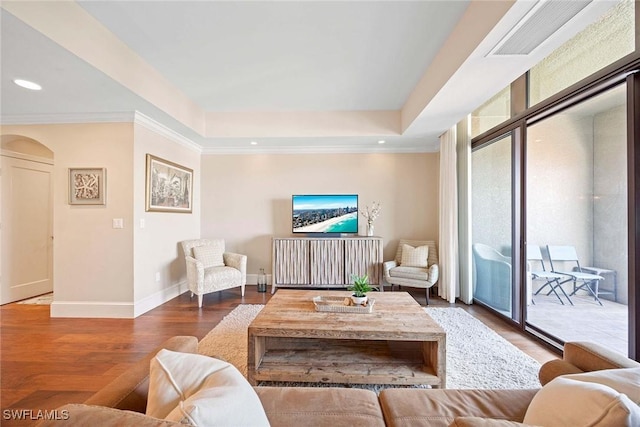 living room with crown molding, a tray ceiling, and wood-type flooring