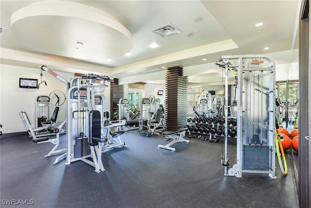 gym featuring plenty of natural light and a tray ceiling