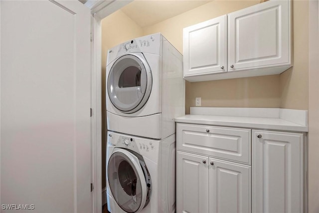 laundry room with cabinets and stacked washer / drying machine