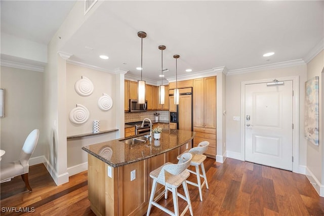 kitchen featuring sink, dark stone countertops, hanging light fixtures, paneled built in refrigerator, and crown molding