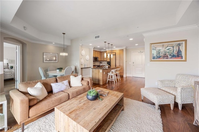 living room featuring a raised ceiling, crown molding, and dark hardwood / wood-style flooring