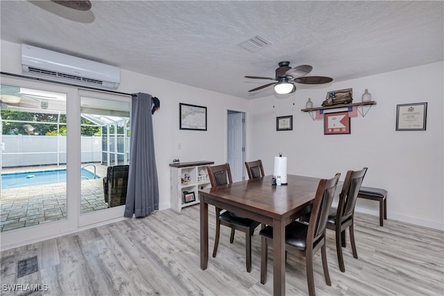 dining area featuring light hardwood / wood-style flooring, a textured ceiling, ceiling fan, and a wall mounted AC