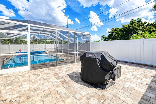 view of swimming pool with glass enclosure, grilling area, and a patio area