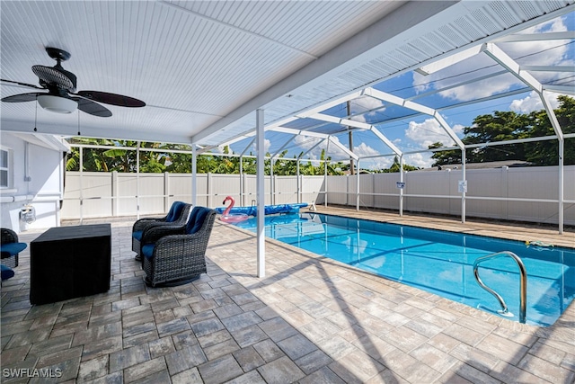 view of swimming pool with ceiling fan, glass enclosure, and a patio area