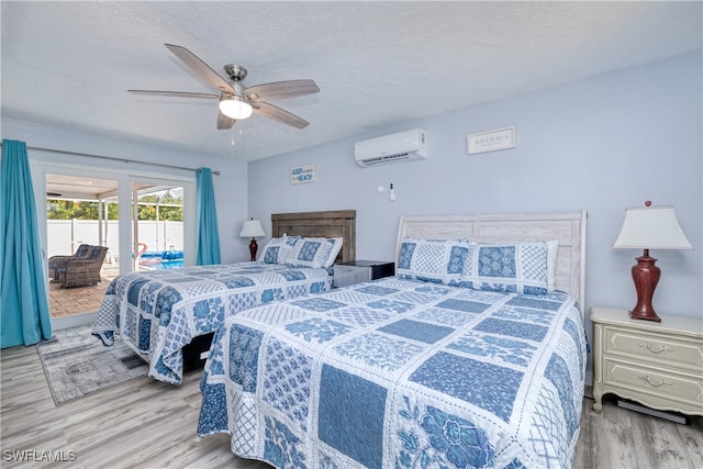 bedroom with ceiling fan, a textured ceiling, hardwood / wood-style flooring, access to exterior, and an AC wall unit