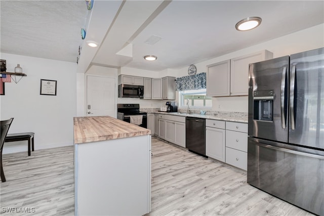 kitchen featuring sink, wooden counters, gray cabinets, appliances with stainless steel finishes, and light hardwood / wood-style floors