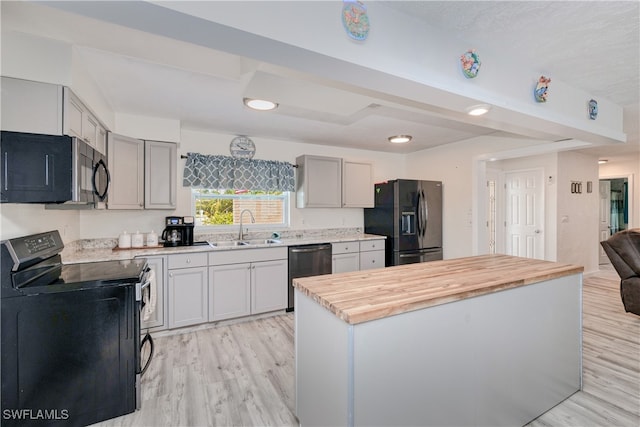 kitchen featuring light hardwood / wood-style floors, butcher block countertops, gray cabinets, black appliances, and sink