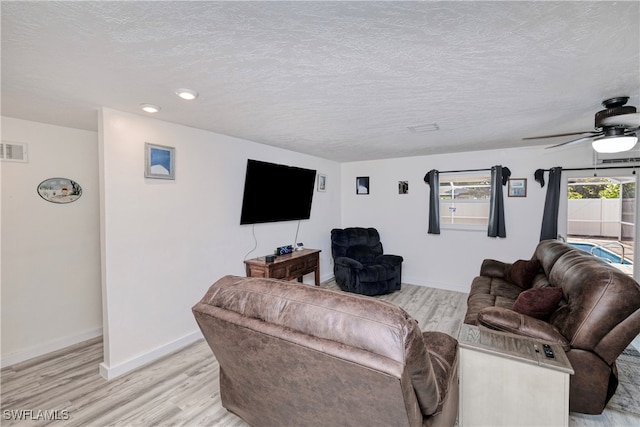 living room with light hardwood / wood-style floors, ceiling fan, and a textured ceiling