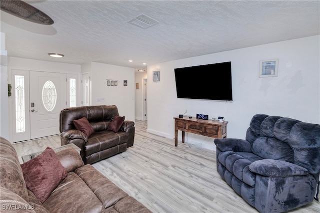 living room with a textured ceiling and light hardwood / wood-style flooring