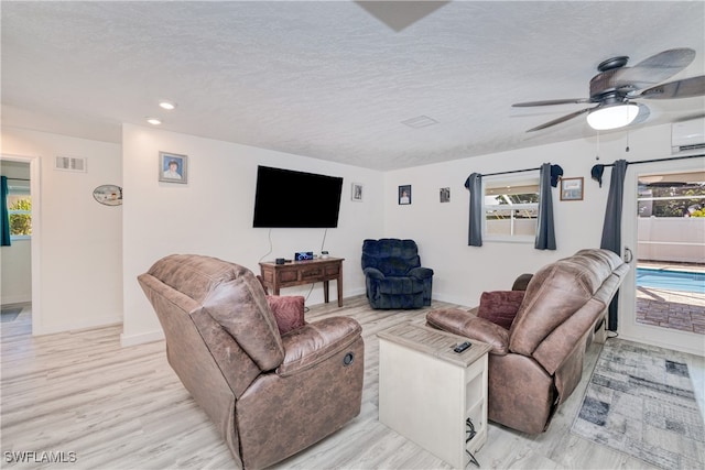 living room with a wealth of natural light, light hardwood / wood-style floors, ceiling fan, and a textured ceiling