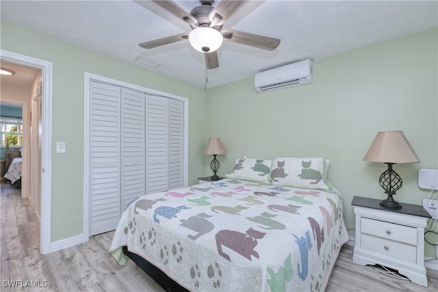 bedroom with an AC wall unit, a closet, ceiling fan, and light hardwood / wood-style flooring