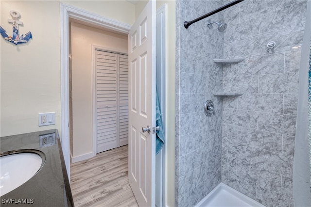 bathroom featuring wood-type flooring, vanity, and tiled shower