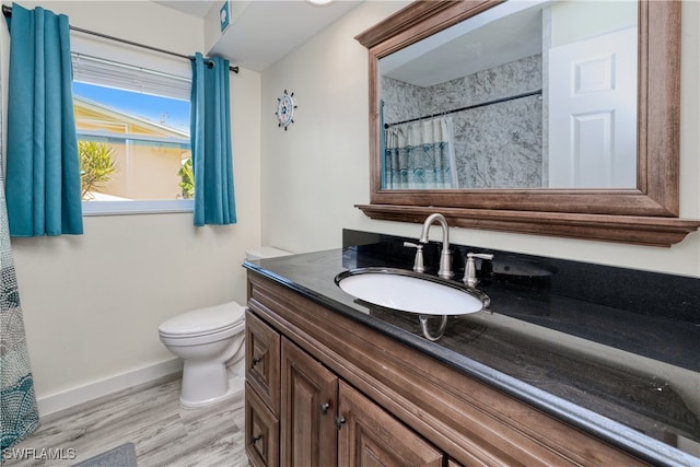 bathroom featuring hardwood / wood-style floors, walk in shower, vanity, and toilet