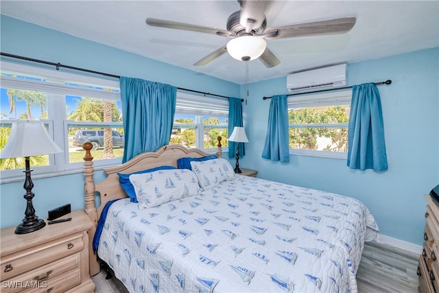 bedroom with ceiling fan, hardwood / wood-style flooring, and an AC wall unit