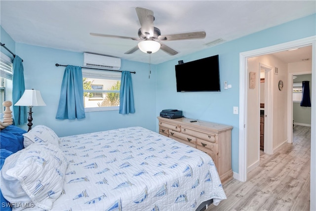 bedroom with ceiling fan, light hardwood / wood-style flooring, and a wall mounted air conditioner