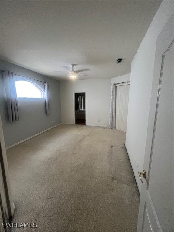 basement with ceiling fan and light colored carpet