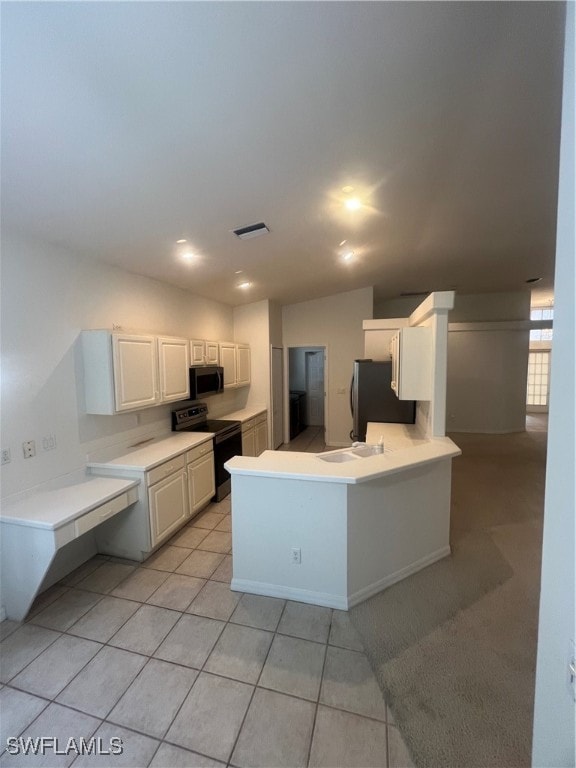 kitchen with appliances with stainless steel finishes, white cabinets, kitchen peninsula, light tile patterned floors, and sink