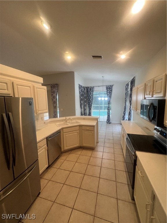 kitchen with pendant lighting, light tile patterned floors, sink, a chandelier, and appliances with stainless steel finishes