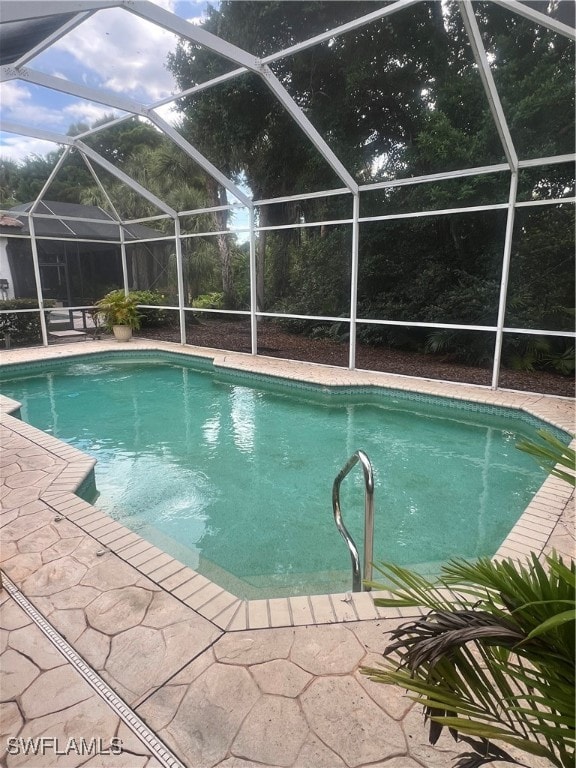 view of swimming pool featuring glass enclosure and a patio area