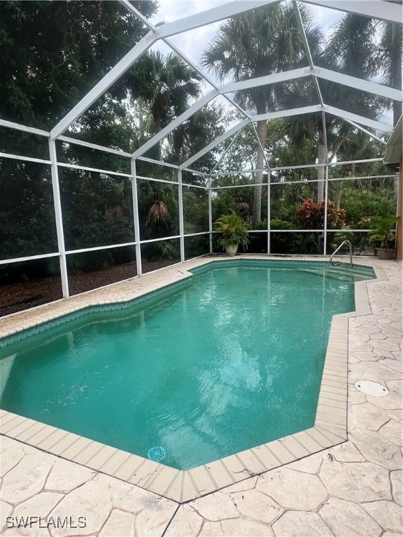 view of pool featuring glass enclosure and a patio area