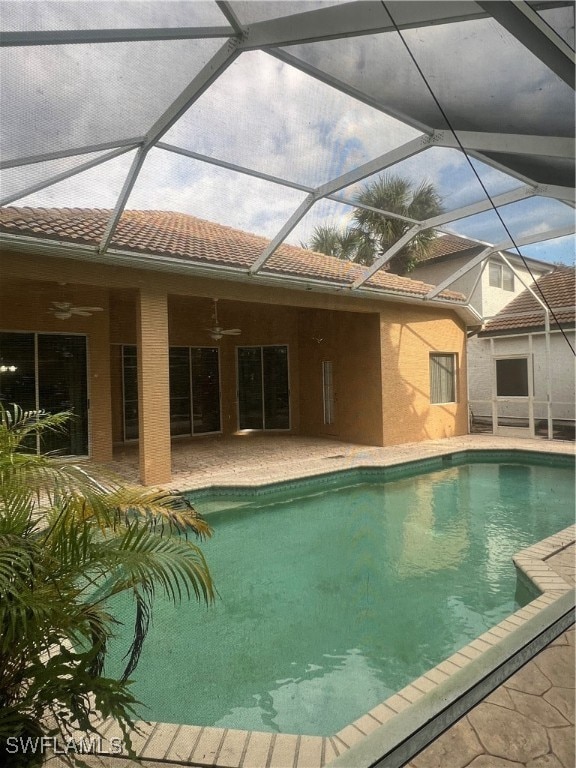 view of swimming pool featuring ceiling fan, a lanai, and a patio area