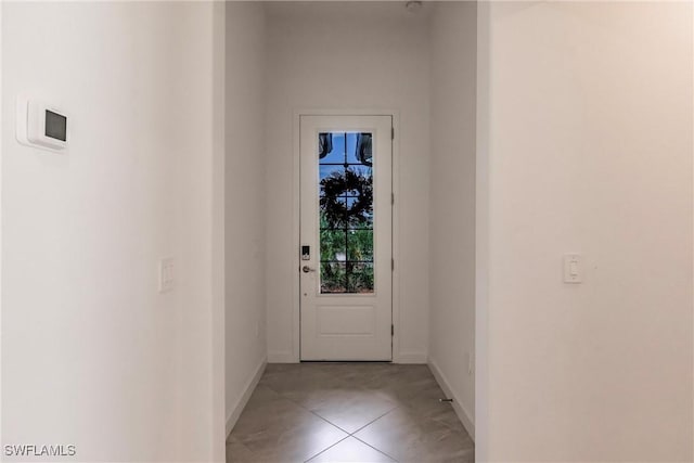 doorway featuring light tile patterned floors and baseboards