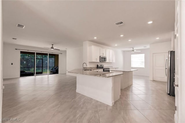 kitchen featuring visible vents, appliances with stainless steel finishes, light stone countertops, white cabinetry, and a sink