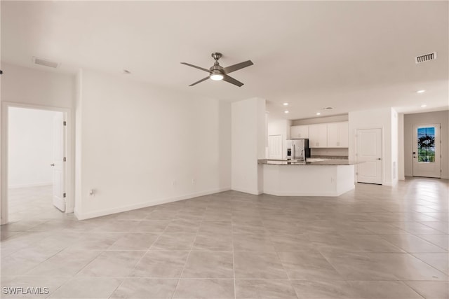 unfurnished living room featuring light tile patterned floors and ceiling fan