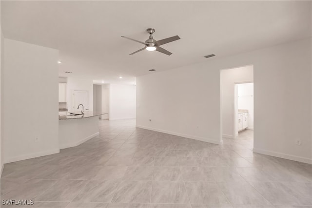 unfurnished living room with sink, ceiling fan, and light tile patterned floors