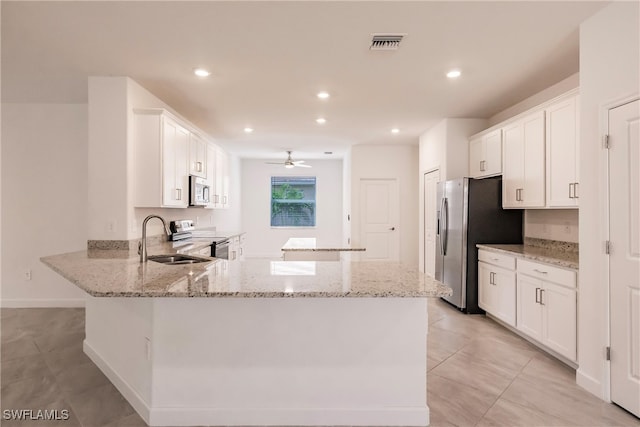 kitchen featuring light stone counters, white cabinetry, kitchen peninsula, and stainless steel appliances