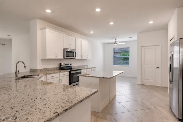 kitchen with kitchen peninsula, white cabinetry, light stone countertops, sink, and stainless steel appliances