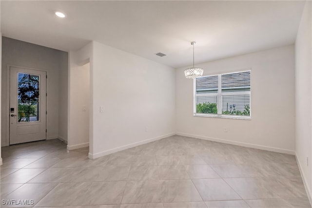 tiled empty room featuring a notable chandelier