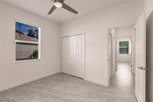 unfurnished bedroom with light tile patterned floors, a closet, and ceiling fan