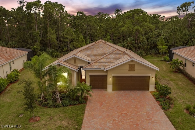 view of front of property featuring an attached garage, stucco siding, decorative driveway, and a front yard