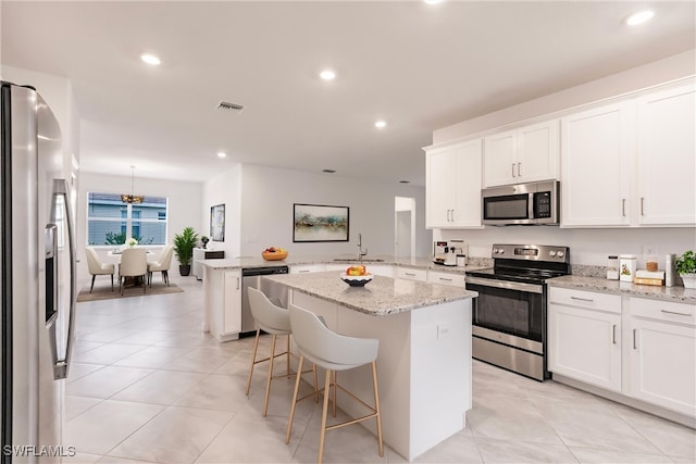 kitchen with a kitchen breakfast bar, a center island, white cabinets, and stainless steel appliances