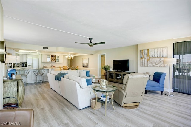 living room featuring ceiling fan with notable chandelier and light hardwood / wood-style floors