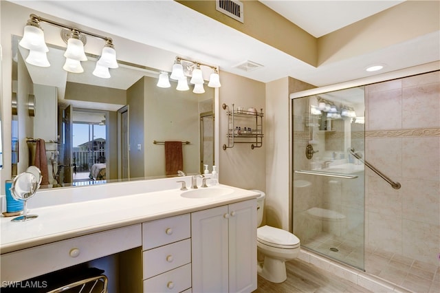 bathroom with vanity, hardwood / wood-style floors, toilet, and a shower with door