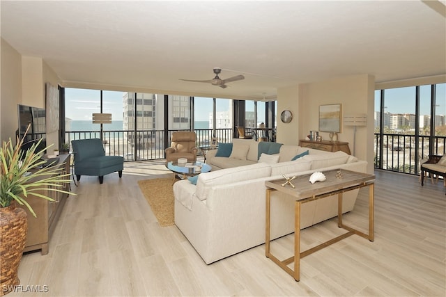 living room with ceiling fan, floor to ceiling windows, light hardwood / wood-style floors, and a water view