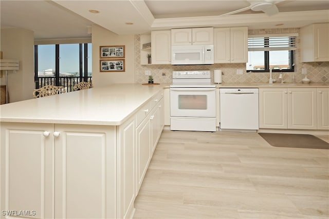 kitchen featuring tasteful backsplash, white appliances, kitchen peninsula, light hardwood / wood-style flooring, and sink