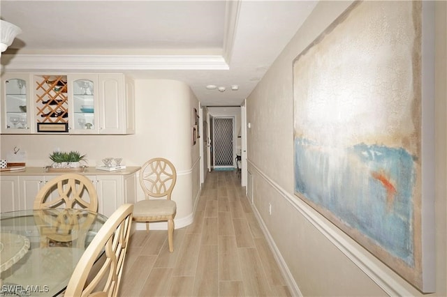 hallway featuring a tray ceiling and light hardwood / wood-style flooring