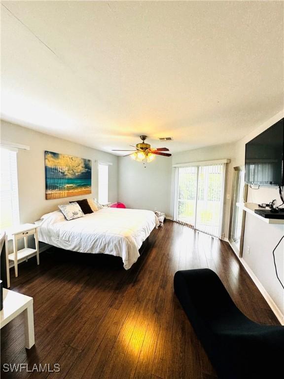 bedroom featuring access to exterior, dark hardwood / wood-style flooring, and ceiling fan