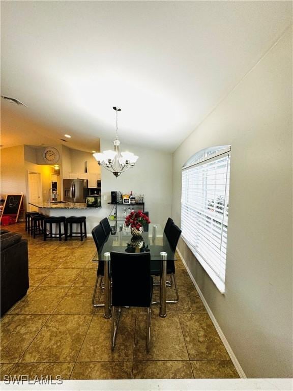 dining area with lofted ceiling and an inviting chandelier