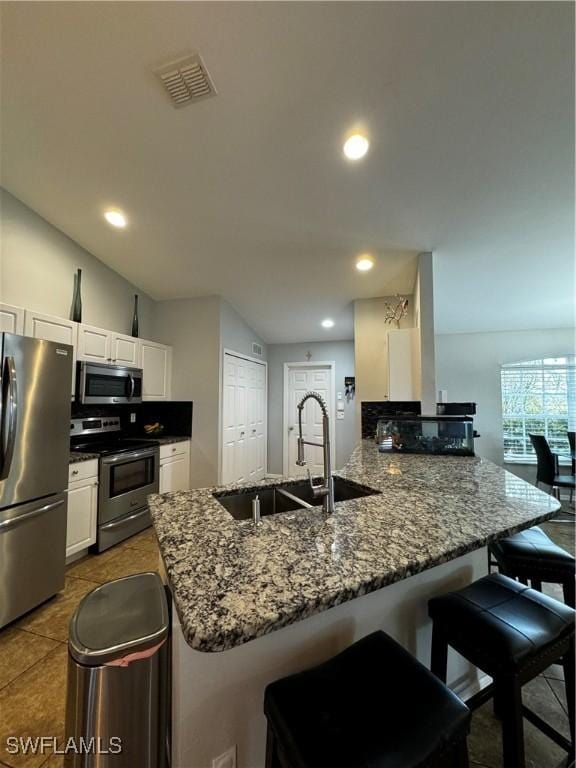 kitchen with kitchen peninsula, a kitchen bar, stainless steel appliances, sink, and lofted ceiling