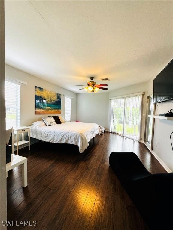 bedroom with access to exterior, multiple windows, dark wood-type flooring, and ceiling fan