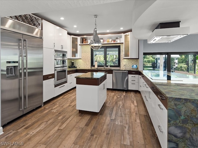 kitchen with pendant lighting, dark wood-type flooring, white cabinetry, stainless steel appliances, and a center island