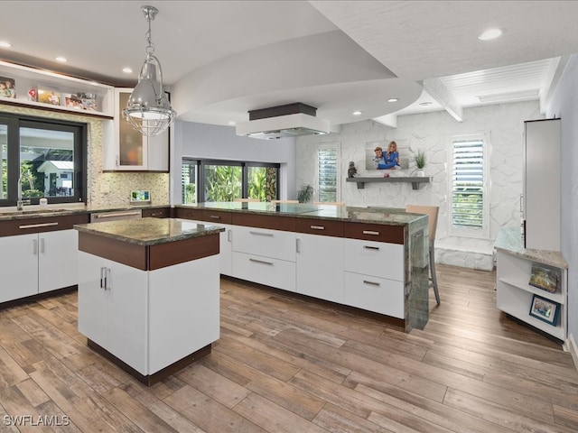 kitchen with wood-type flooring, beamed ceiling, white cabinetry, and a center island