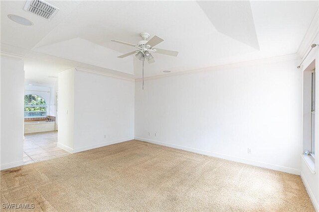 unfurnished room featuring crown molding, ceiling fan, light colored carpet, and a raised ceiling